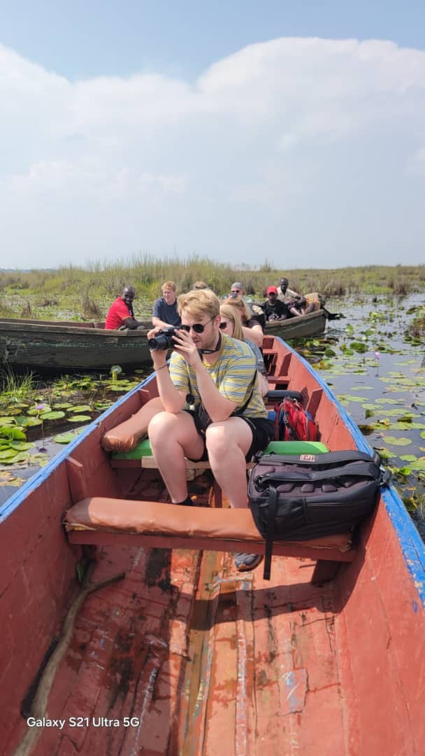 A traveller photographing wildlife from a wooden canoe on Lake Victoria